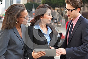 Businessman And Businesswomen Using Digital Tablet Outside