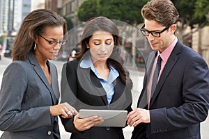 Businessman And Businesswomen Using Digital Tablet Outside