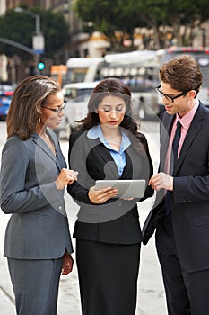 Businessman And Businesswomen Using Digital Tablet Outside