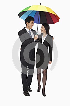 Businessman and businesswomen walking under colorful umbrella, studio shot