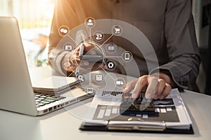 Businessman calculates financials with graph paper on the laptop computer, cell phone on the cost.