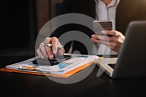 Businessman calculates financials with graph paper on the laptop computer.