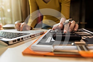 Women calculates financials with graph paper on the table on the cost of home office.