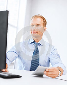 Businessman with calculator, computer and papers