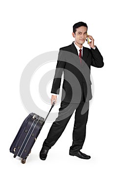 Businessman on call pulling travel bag