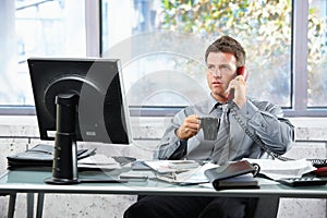 Businessman calling at office with mug