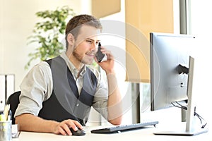 Businessman calling on phone and using a computer photo