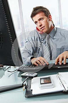 Businessman calling typing in office