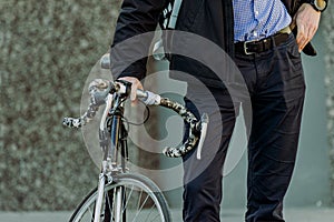 Businessman came to work on a bicycle. a man stands next to a bicycle