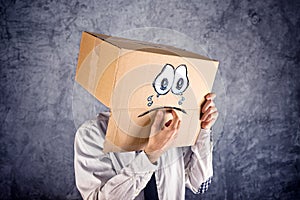 Businessman with cardboard box on his head and sad face expression