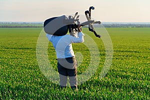 Businessman carries an office chair in a field to work, freelance and business concept, green grass and blue sky as background