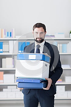 Businessman carrying a box and office folders