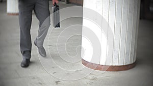 Businessman carrying briefcase while moving forward. Man in formalwear walking near modern office building, full length