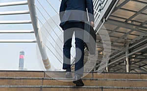 businessman carrying a briefcase walking up the stairs in the city