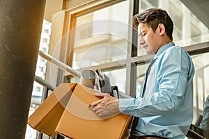 Businessman is carrying a brown cardboard box to resignation