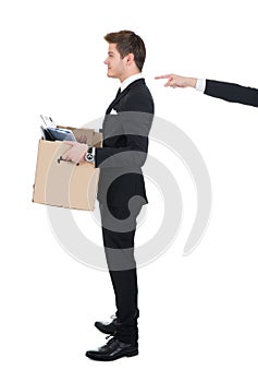 Businessman carrying cardboard box with hand pointing at him