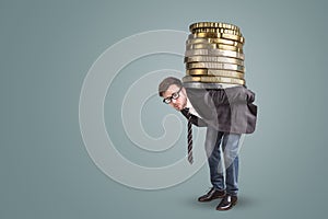 Businessman carrying a giant stack of coins on his back