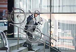 Businessman carrying his bike