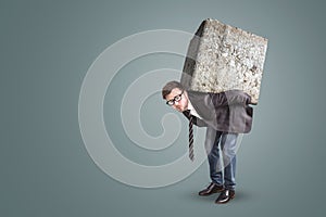 Businessman carrying a large and heavy stone on his back
