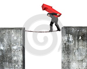 Businessman carrying red arrow sign balancing on rusty chain