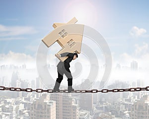 Businessman carrying wooden house balancing on chain