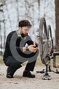 Businessman in casual attire repairing a bicycle in a park setting