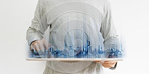 Businessman in casual clothing using digital tablet, with Hologram futuristic modern buildings, on white background. Real estate a