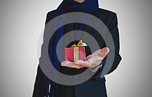 Businessman in casual suit with little gift box on hand, selective focus on gift box