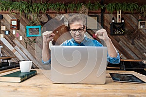 Businessman celebrating in front of his laptop excited