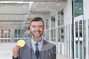 Businessman celebrating while holding a huge coin