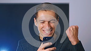 Businessman Celebrating Success while Reading Message in Smartphone. Handsome professional successful business man