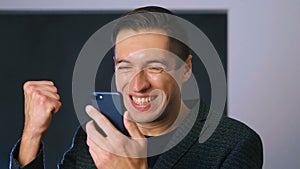 Businessman Celebrating Success while Reading Message in Smartphone. Handsome professional successful man achieving