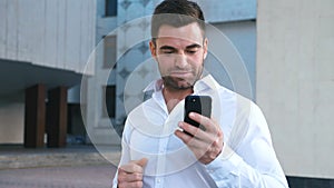 Businessman Celebrating Success while Reading Message in Smartphone near office building. Handsome professional