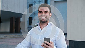 Businessman Celebrating Success while Reading Message in Smartphone near office building. Handsome professional