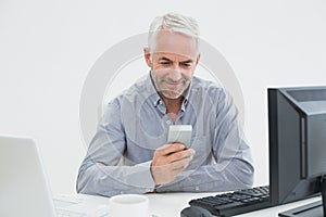 Businessman with cellphone, laptop and computer at desk