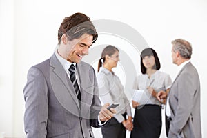 Businessman, cellphone and smile or team background, job communication or online planning. Male person, mobile decisions