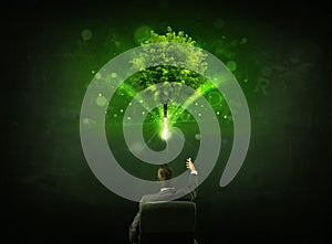 Businessman in chair sitting in front of a glowing tree