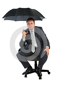 Businessman on chair with umbrella