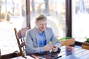 Businessman chatting at cafe by smartphone near tablet.