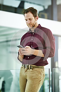 Businessman, chatting and typing with phone at office for networking, communication or sending message. Young man or