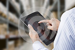 Businessman checking inventory in stock room of a manufacturing company on tablet photo