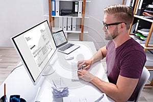 Businessman Checking Invoice On Computer