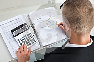 Businessman Checking Invoice With Magnifying Glass