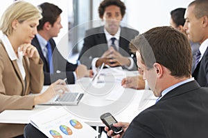 Businessman Checking Phone During Meeting In Office