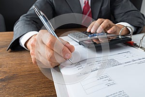 Businessman Checking Receipts At Desk