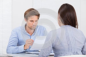 Businessman Checking Resume Of Female Candidate During Meeting