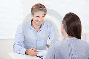 Businessman checking resume of female candidate during meeting