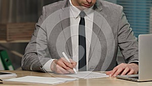 Businessman checking and signing by pen contract. Boss in business suit sits at table in office. Signing on papers