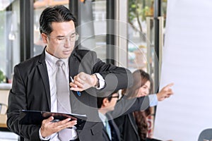 Businessman checking time. business people holding job broad and pen looking at his wrist watch. Handsome man standing