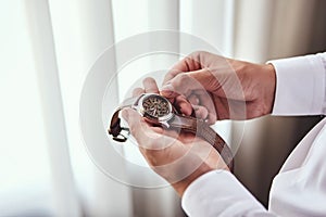 Businessman checking time on his wrist watch, man putting clock on hand,groom getting ready in the morning before wedding ceremony